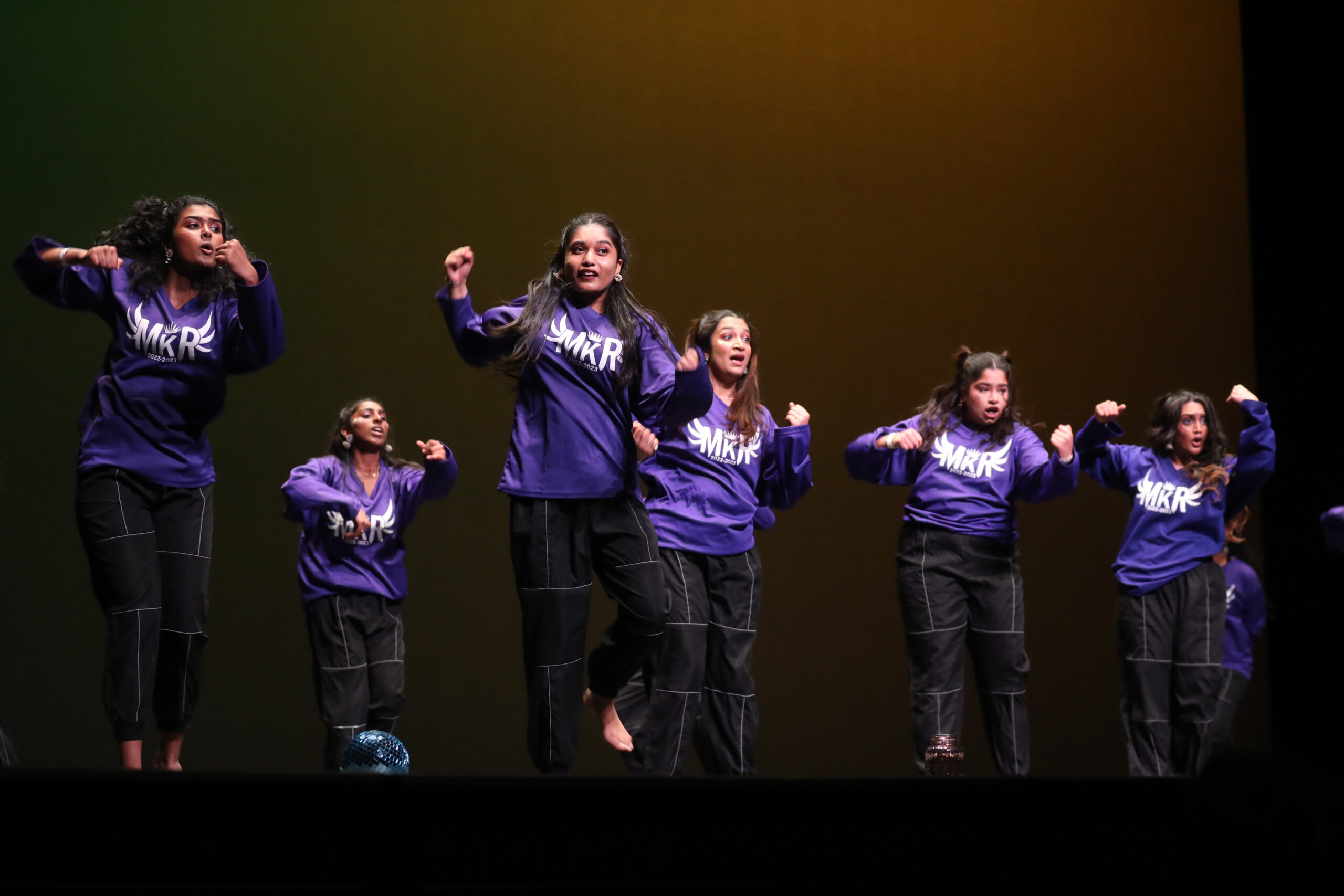 6 girl students wearing similar costumes and perfroming dance.
